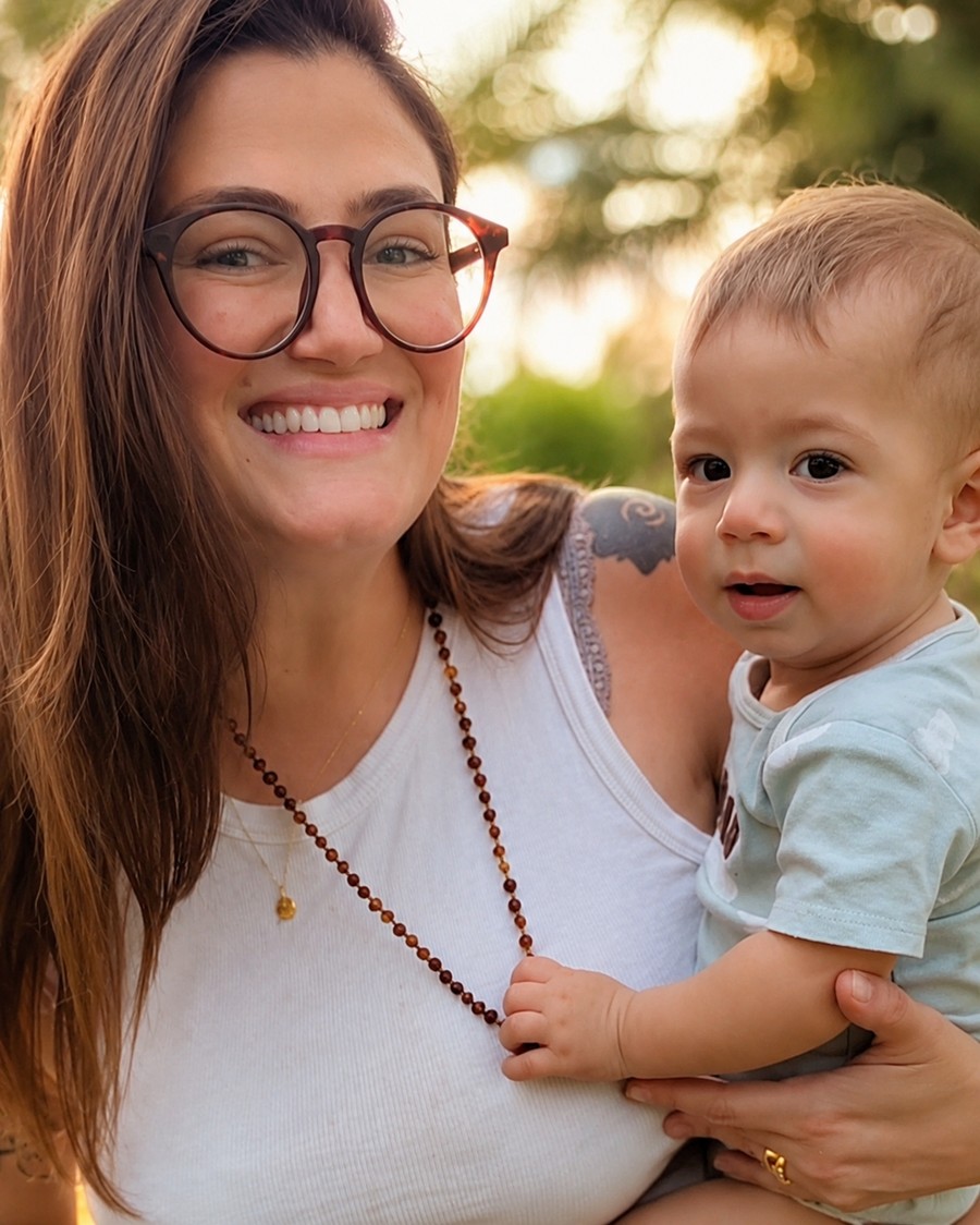 Mãe sorridente segurando seu bebê no colo, em um jardim